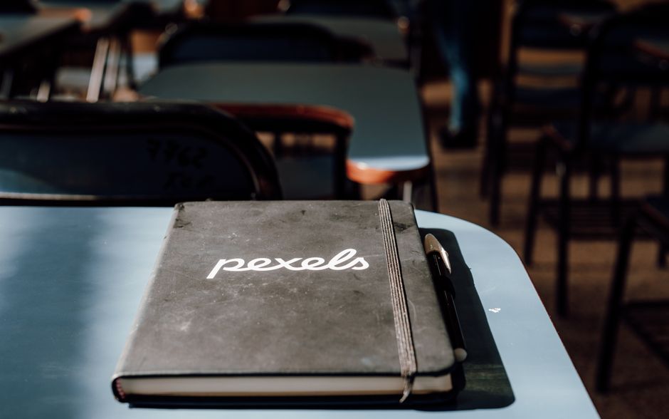 A close-up of a notebook and pen in a classroom setting
