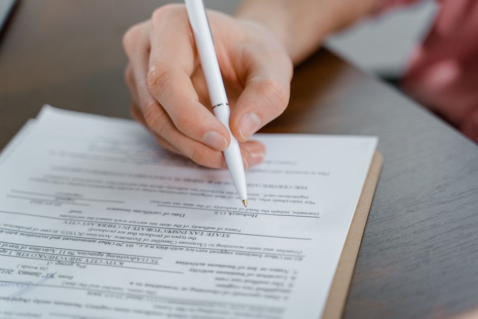 A hand holding a pen signing a document