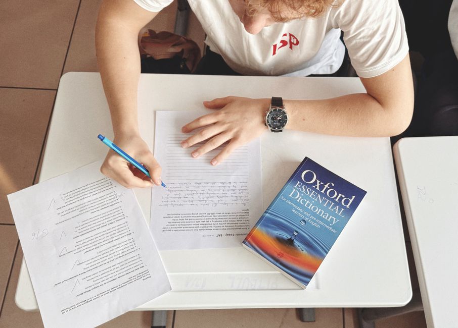 Student writing a placement test with paper and dictionary
