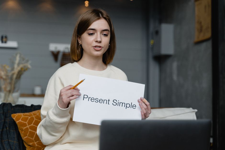 Young woman teaching English grammar online with a presentation