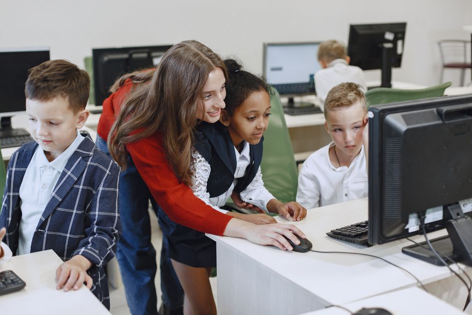 Teacher engaging with diverse children in a technology lesson