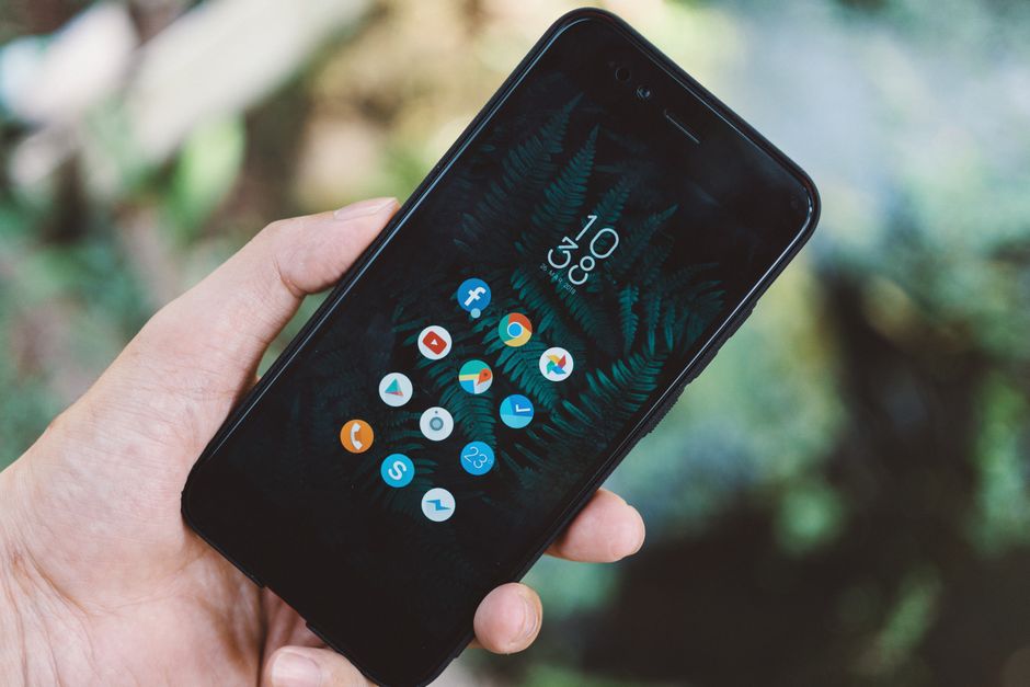 Close-up of a hand holding a smartphone with app icons and a