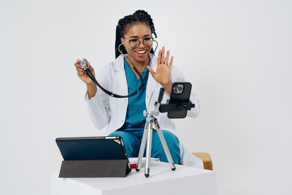 Smiling female doctor using stethoscope during a telehealth consultation