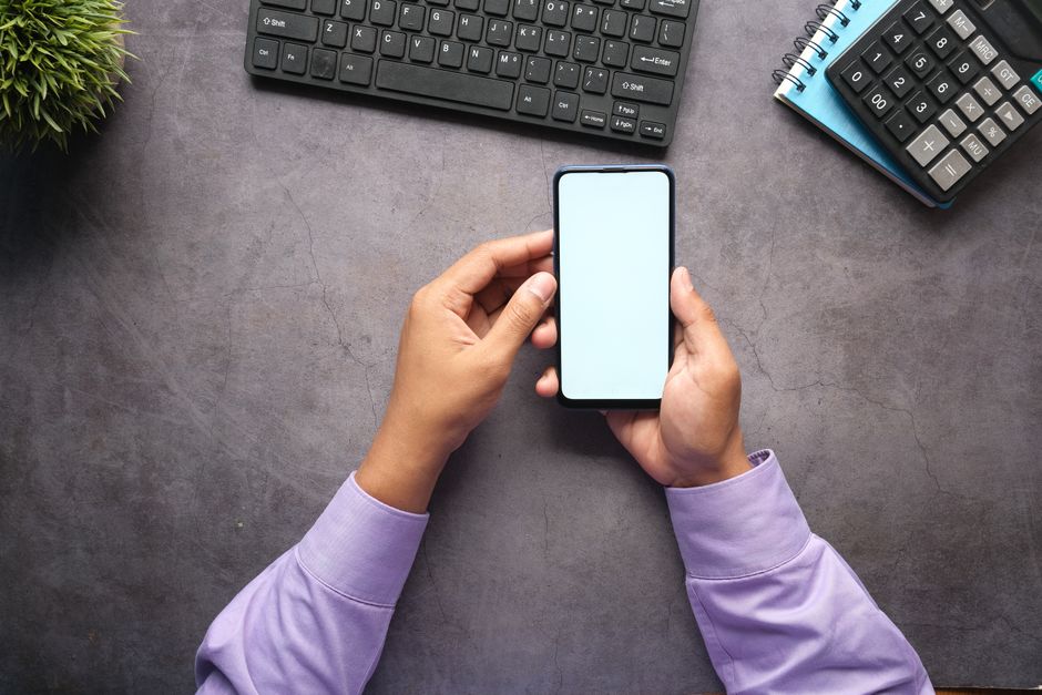 Man in purple shirt holding a smartphone with blank screen