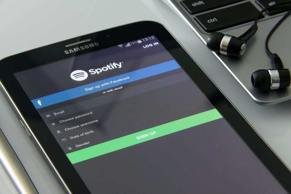 Smartphone showcasing Spotify login beside laptop