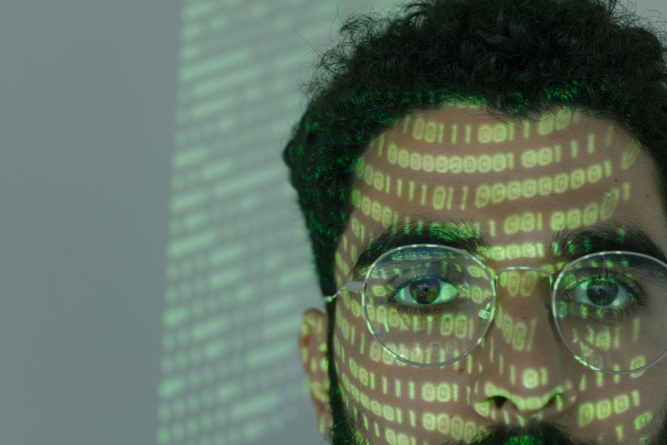 Close-up of a man with binary code projected on his face
