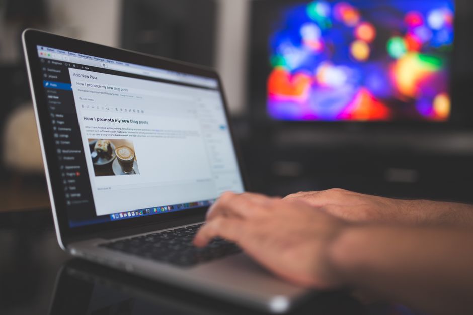 Hands typing on a laptop with a blog post visible