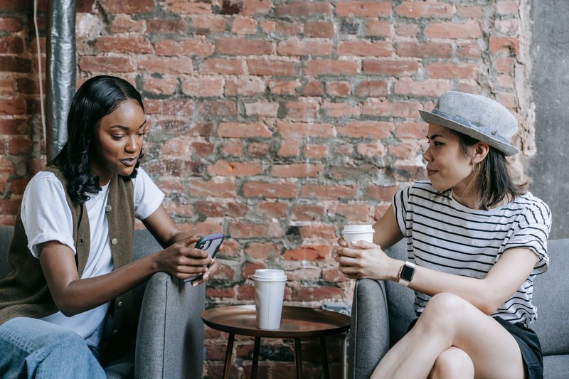 Two friends enjoying a coffee break indoors, sharing moments and conversations.
