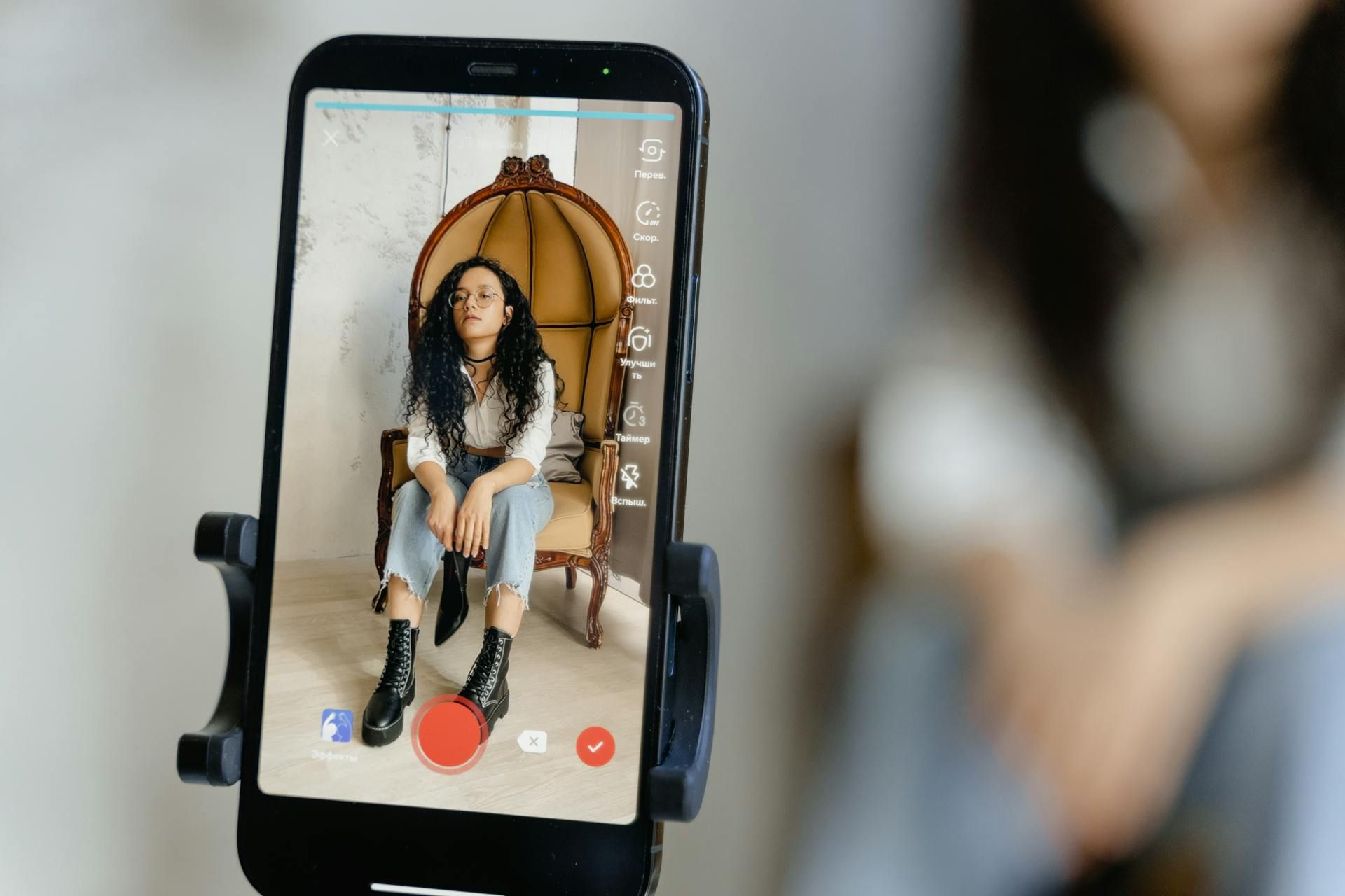 Woman recording herself sitting in a chair.