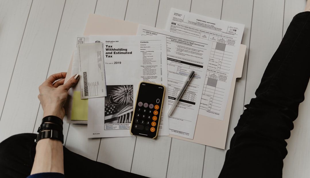 A person reviewing financial tax documents at a desk with a calculator