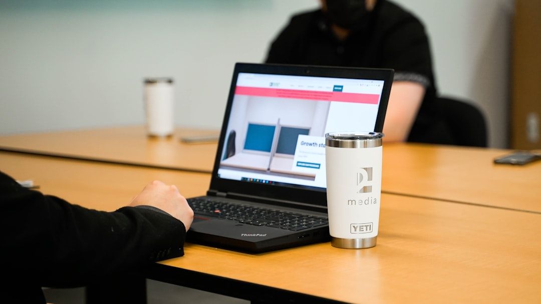 A laptop showing spreadsheets beside paper folders on a meeting room table