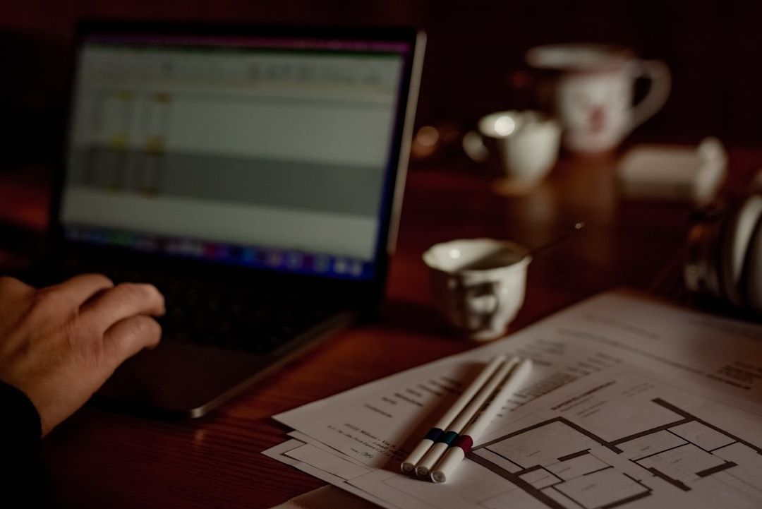 A person reviewing property documents beside a laptop at a desk