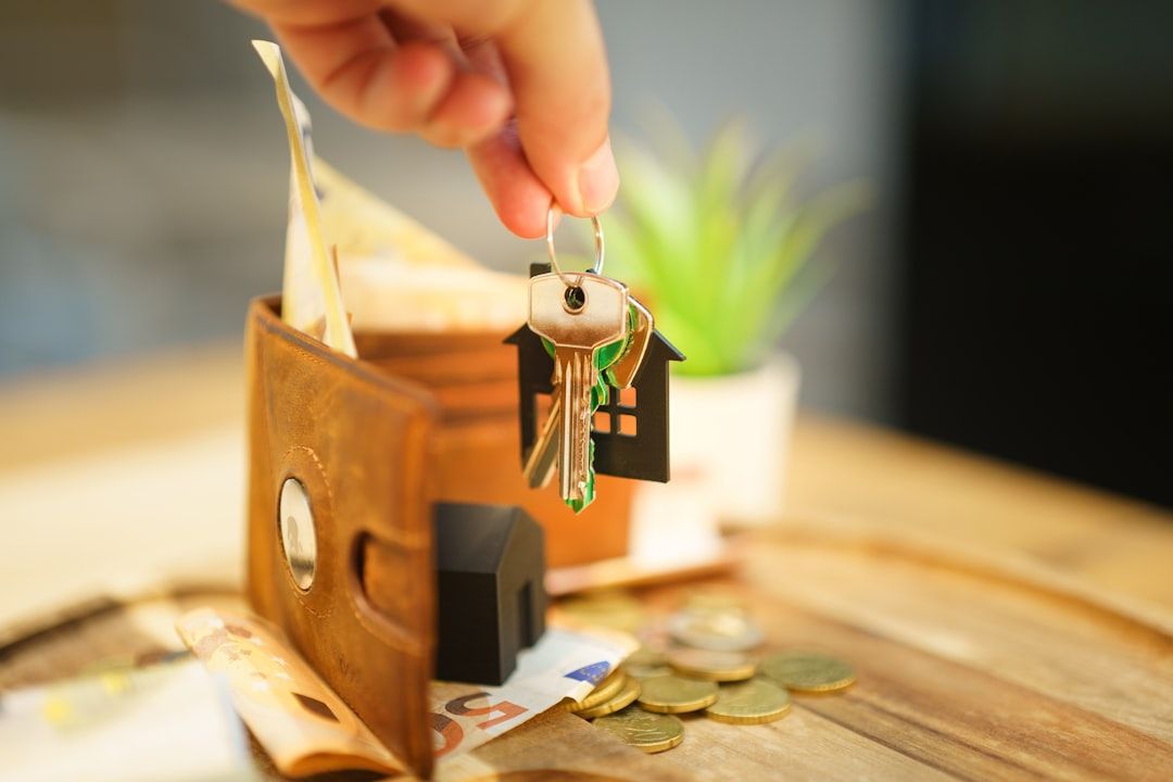 Hands signing property closing documents at a desk beside a set of house keys