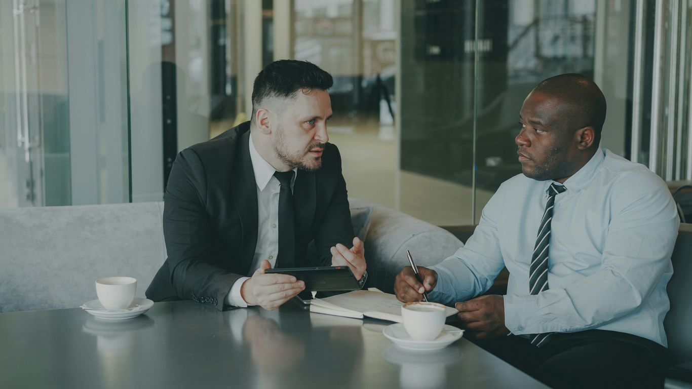 Two businessmen discussing work over coffee.