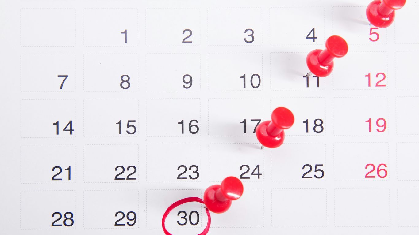 a calendar with red push buttons pinned to it