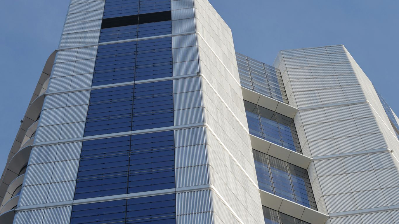 A tall white building with blue windows against a blue sky