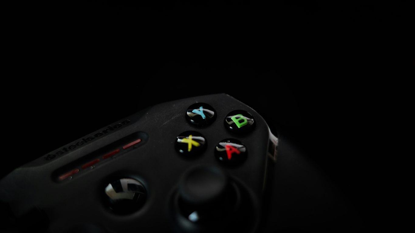 Close-up of a black video game controller with colorful buttons