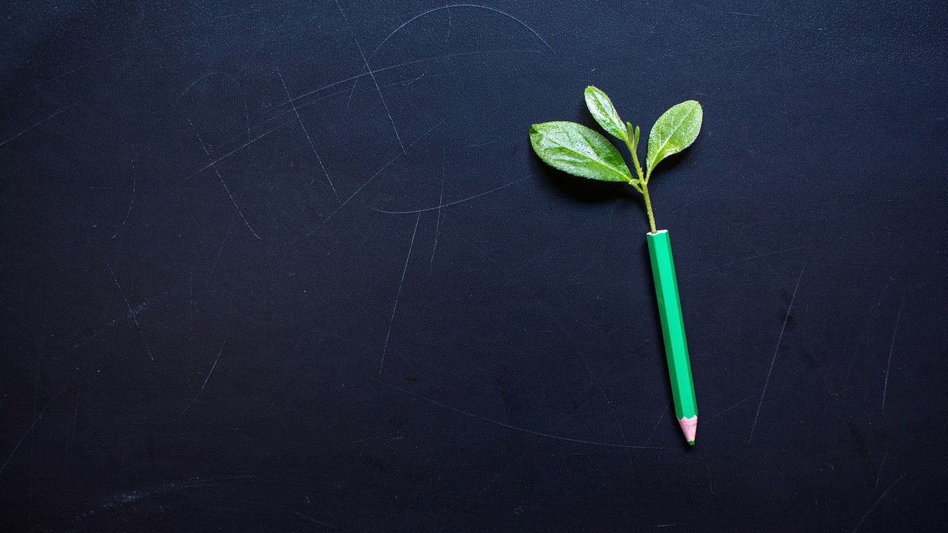 a green pencil resting on a black surface