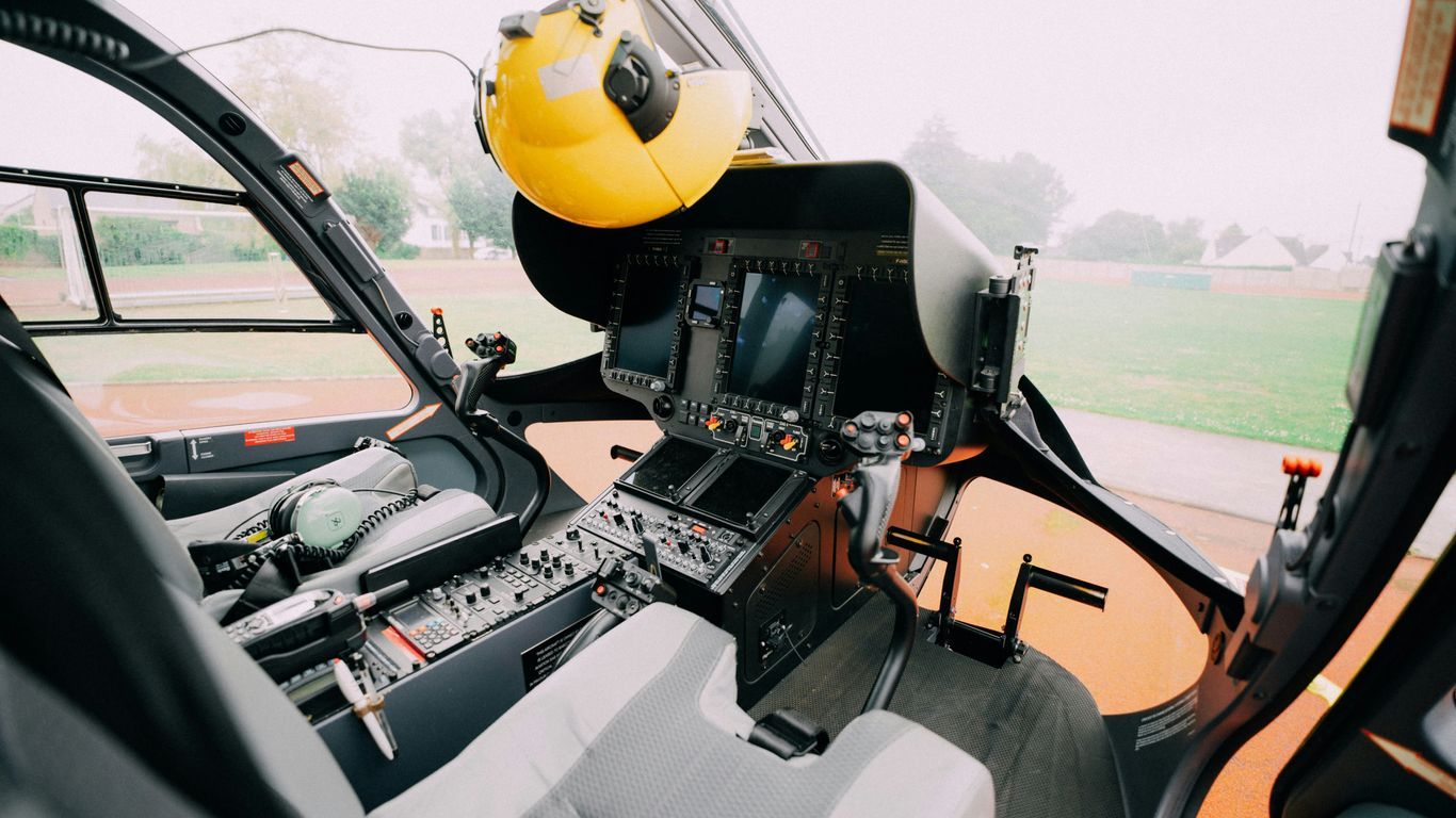 the cockpit of a helicopter with a yellow helmet on