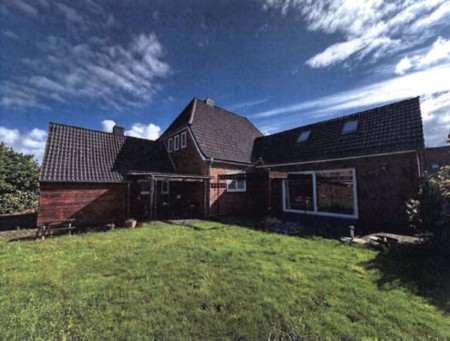 Einfamilienhaus mit dunklem Satteldach und Holzfassade, Vorgarten mit Rasen, Hauptstraße 26, 25866 Mildstedt