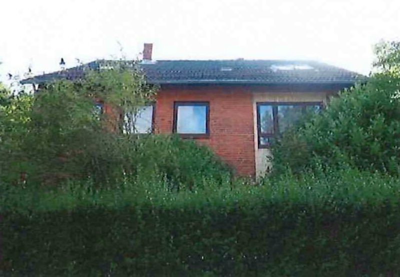 Seitenansicht eines Mehrfamilienhauses mit roten Ziegelwänden, dunklem Dach und Fenstern, teilweise von Büschen verdeckt, Heikendorfer Weg 74, 24149 Kiel