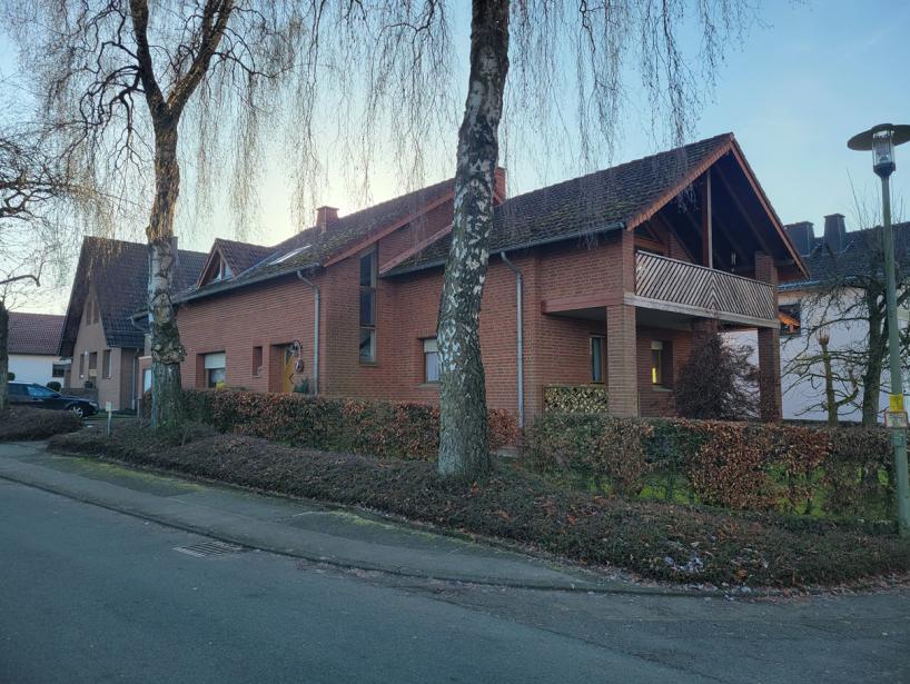 Zweifamilienhaus aus Backstein mit Satteldach, Balkon und Hecke im Vorgarten, Ansicht von der Straße in Lichtenau, Sandheide 10