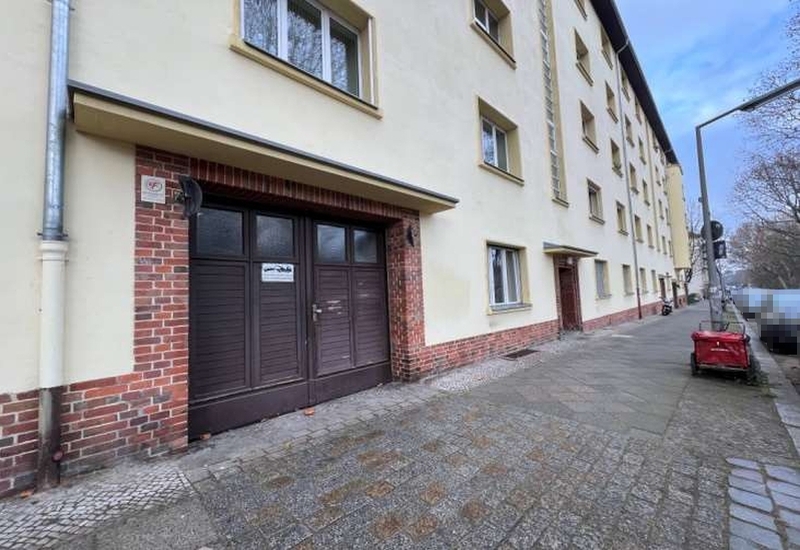 Eingangsbereich eines Mehrfamilienhauses in Berlin-Schöneberg, Baumeisterstraße 2/3, mit braunen Türen, rotem Ziegelsockel und beigefarbener Fassade