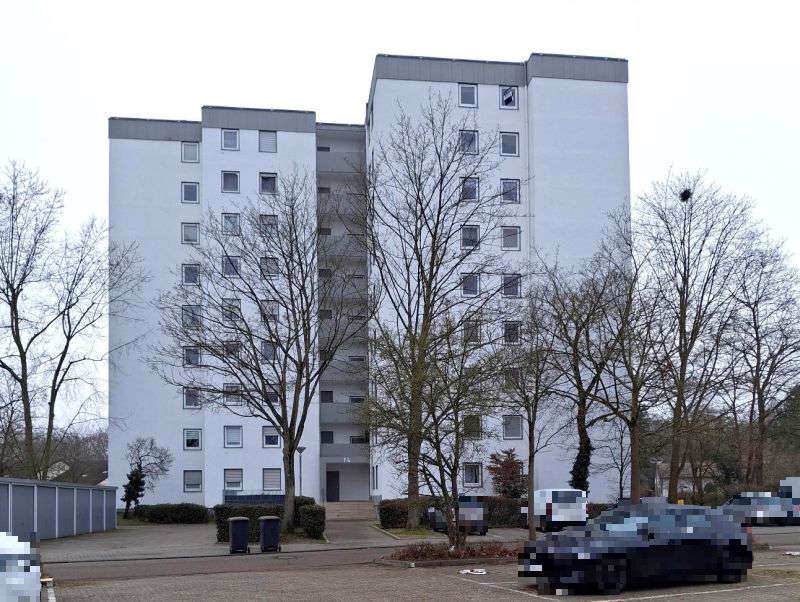 Fassade eines weißen Mehrfamilienhauses in Limburgerhof, Schlesier Straße 14, mit kahlen Bäumen und geparkten Autos vorne
