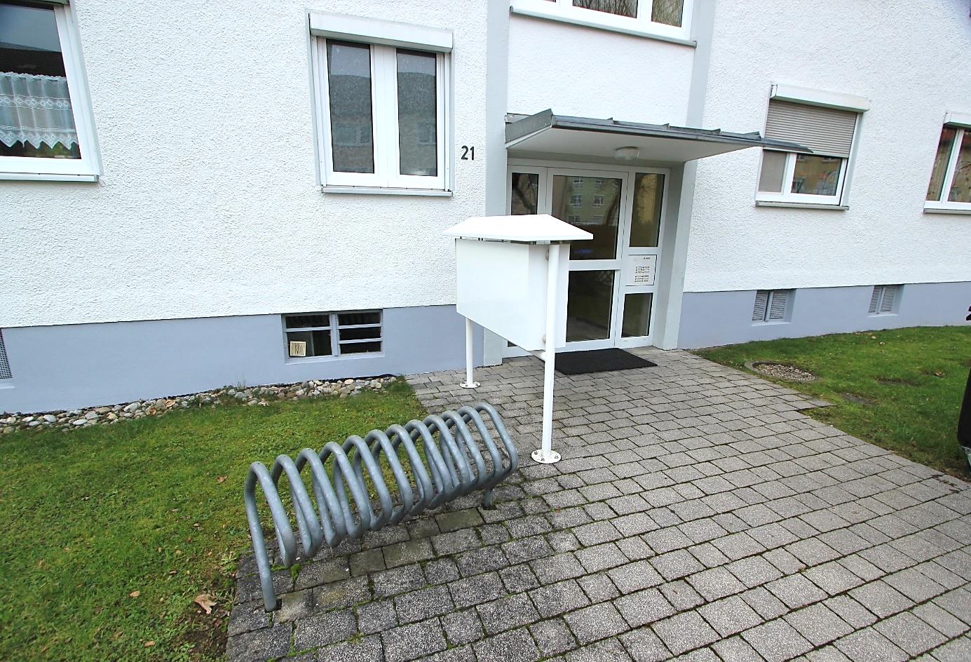 Eingangsbereich der Eigentumswohnung Harderstraße 21 in Senden mit Eingangstür, Briefkasten, Fahrradständer und gepflastertem Weg
