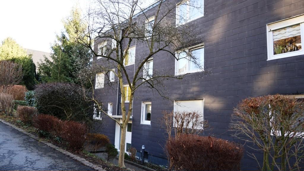 Seitenansicht eines Mehrfamilienhauses mit dunkler Fassade, Fenstern und Beeten mit Sträuchern in Gevelsberg, Südstraße