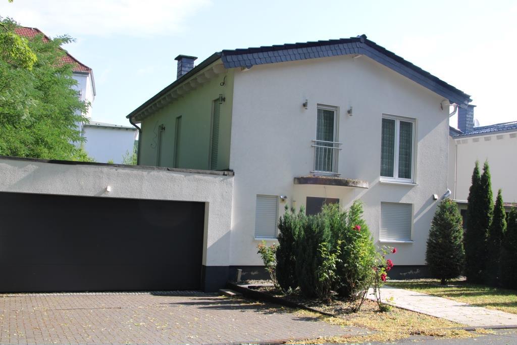 Vorderansicht eines zweistöckigen Reihenhauses mit weißer Fassade, grüner Seitenwand, Garage und Vorgarten in Hagen, Mühlhauser Straße 28