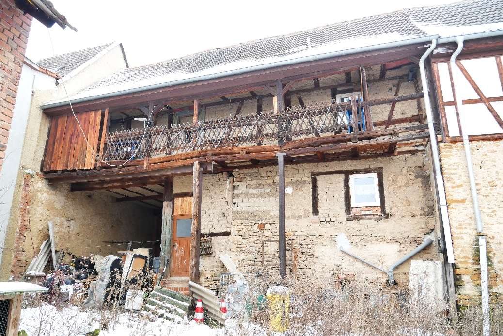 Seitenansicht eines verputzten Steinbaus mit Holzverkleidung und Balkon, Eingangsbereich mit Garage, verschneiter Garten, Mannstedt, Langestraße 13