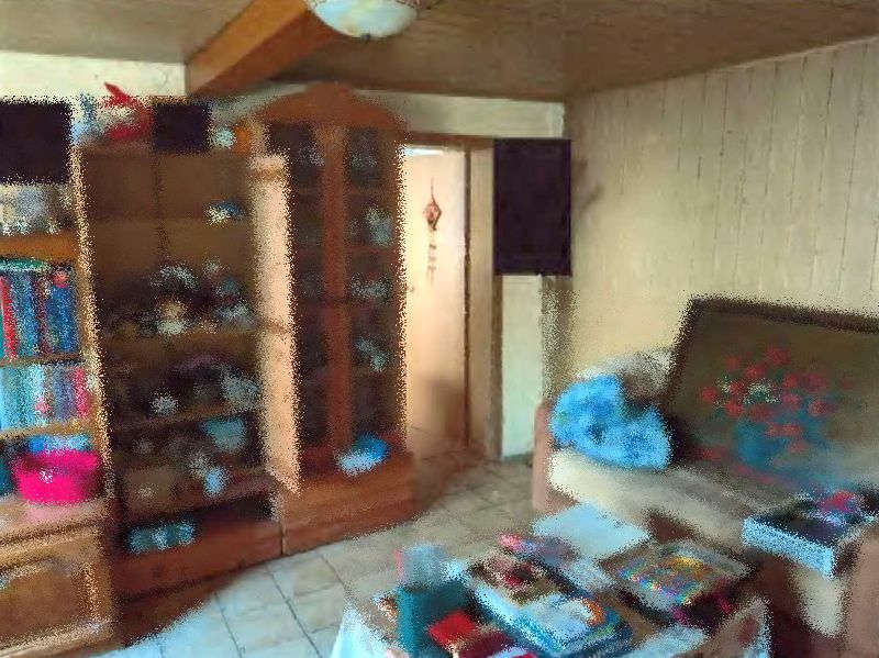 Wohnzimmer mit Holzregal, Vitrine, Sofa und Tisch, Fliesenboden, Holzdecke, Tür im Hintergrund