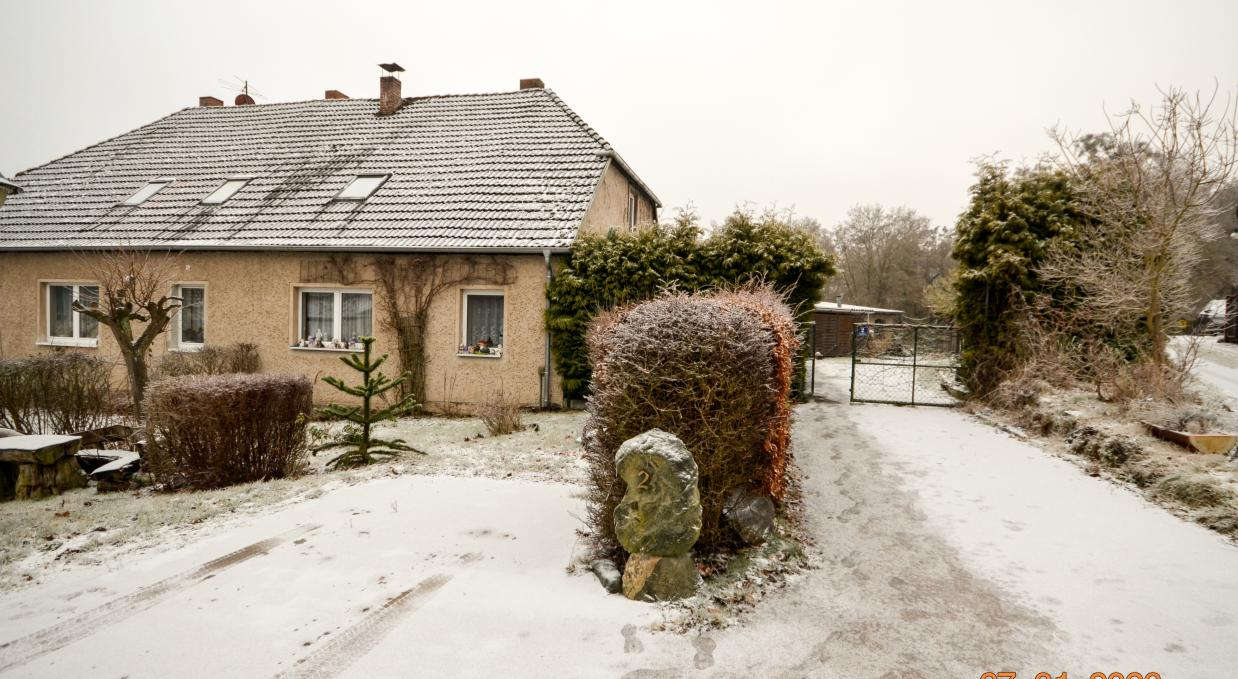 Garten des Einfamilienhauses Am Schmiedeberg 2 in Boitzenburger Land, 17268, mit Schneebedeckung, Hecken, Steinen und Eingangstor
