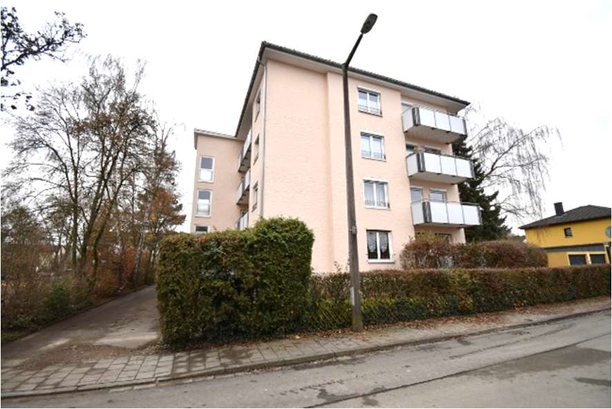 Seitenansicht eines mehrstöckigen Wohnhauses mit Balkonen, umgeben von Hecken und Bäumen, an der Falkenstraße in Erlangen