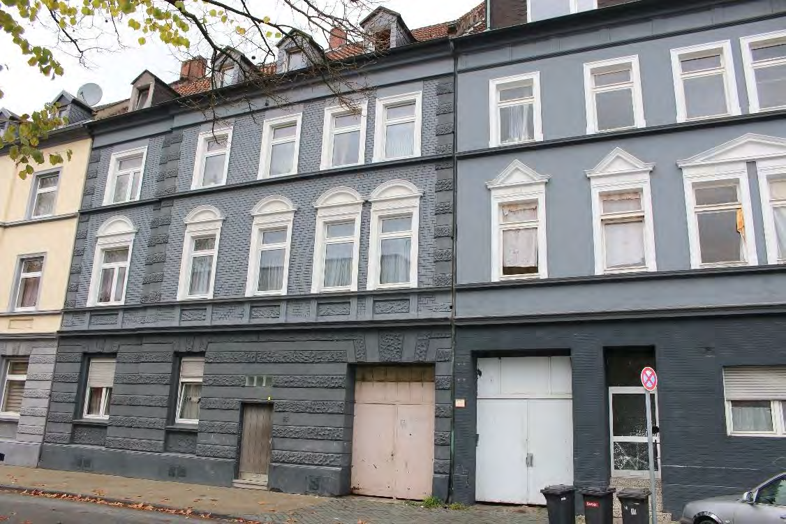 Fassade eines mehrstöckigen Gebäudes in Gelsenkirchen, Franz-Bielefeld-Straße 65, mit mehreren Fenstern und Garagen im Erdgeschoss