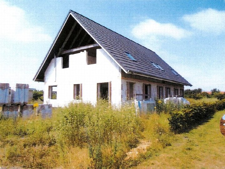 Einfamilienhaus im Rohbau mit weißer Fassade und dunklem Satteldach, umgeben von Grünflächen, Geestbogen 16a, 16b, Klixbüll, 25899