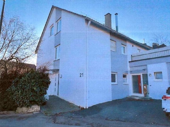 Einfamilienhaus mit weißer Fassade, Hausnummer 21, Ziegeleistraße 21, Ditzingen. Sichtbar sind Fenster, Dach, Schornsteine und ein Vorgartenbereich