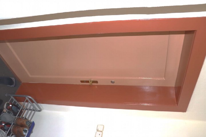 Innenansicht einer Garage mit rostbraunem Türrahmen und Schuhregal im Vordergrund