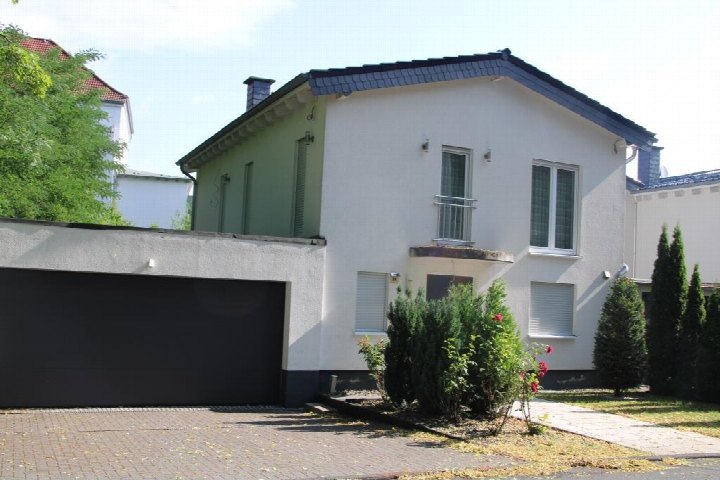Vorderansicht eines zweistöckigen Reihenhauses mit weißer Fassade, grüner Seitenwand, Garage und Vorgarten in Hagen, Mühlhauser Straße 28