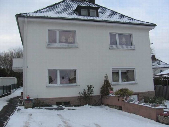 Seitenansicht eines zweistöckigen weißen Wohnhauses mit Schneebedeckung, Fenstern und Gartenbeeten im Winter, Im Hohen Felde 2, Höxter